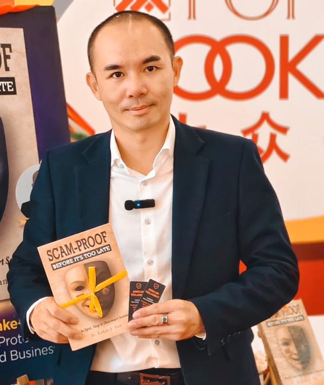 Ts. Lukas J. Tan, author of Scam-Proof and ScamAlert Junior, holding a copy of Scam-Proof